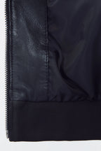 Front studio shot of a man wearing a slim-fit black leather bomber jacket with a snap-tab collar and zippered pockets, styled with dark pants against a white background.