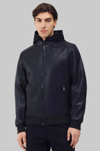 Front studio shot of a man wearing a slim-fit black leather bomber jacket with a snap-tab collar and zippered pockets, styled with dark pants against a white background.